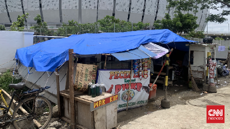 Megah JIS di Antara Ratap Anak-anak Tenda Warga Kampung Bayam Rumah Agus telah disulap menjadi JIS. Kini Agus tinggal berjejal bersama empat kepala keluarga lain di sebuah tenda biru, tak jauh dari bangunan megah JIS.