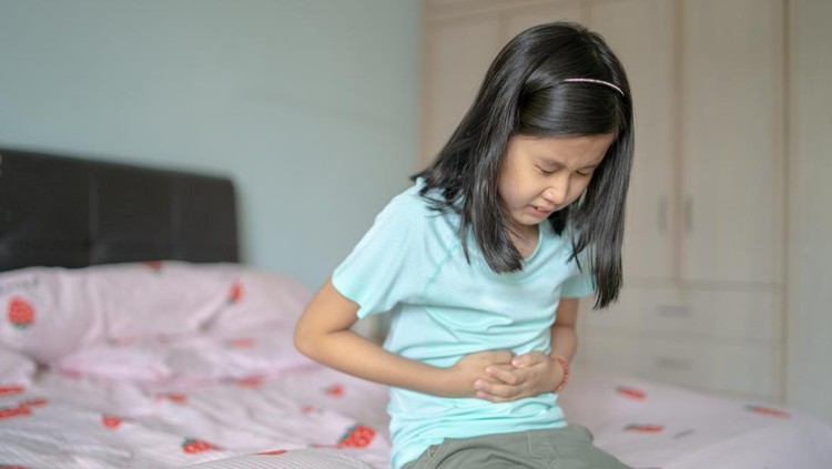Ilustrasi Masalah Pencernaan pada Anak An Asian Chinese girl having a stomach ache at home.