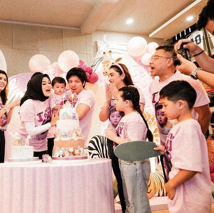 <p>Di acara ultah Ameena ini, keluarga Aurel dan Atta kompak mengenakan kaus berwarna pink dengan tulisan '1st Birth Day' dan foto menggemaskan Ameena. (Foto: Instagram @aurelie.hermansyah/ @krisdayantilemos)</p>