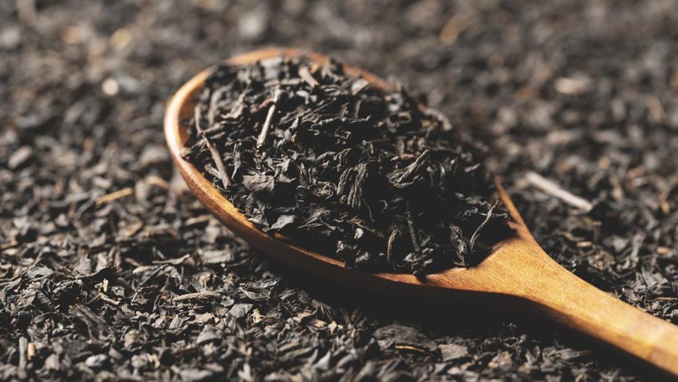 Background with tea leaves and a wooden spoon for the entire screen. Close-up.