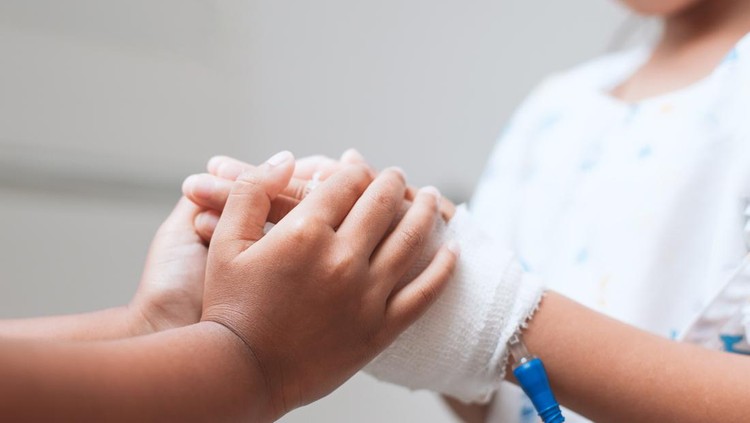 Child girl holding sick young sister hand who have IV solution bandaged with love and care in the hospital