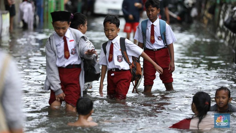 Warga beraktifitas saat banjir setinggi 60 cm menggenangi kawasan Pesing Koneng, Jakarta, Senin (27/2/2023). (CNBC Indonesia/Tri Susilo)