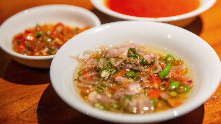 Close up shot of delicious spicy Balinese raw chili chopped with shallot and lemongrass ( sambal matah bali ). There's various chili condiment on the side.