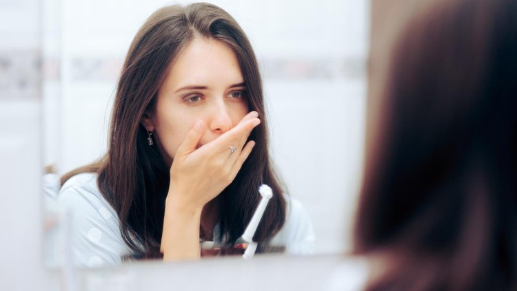 Young adult suffering from sore gums, gingivitis, and other untreated dental health problems