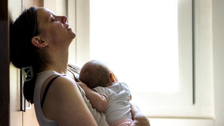 Mother embracing her baby girl while sleeping,lifestyle concept.Tired concerned mother rocking sleeping baby in kitchen.Portrait of young woman and cute little baby in home interior.Motherhood concept
