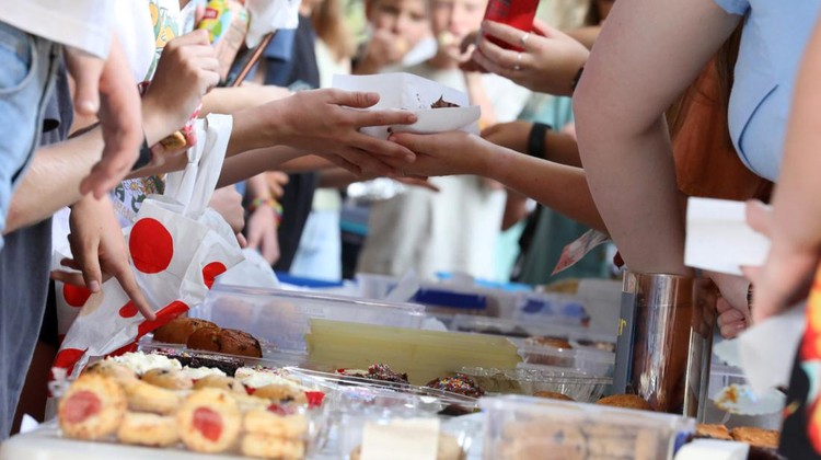 jual kue A close up of hands and food exchanging at a communty fair, fete or market stall. A typical bake or cake sale.