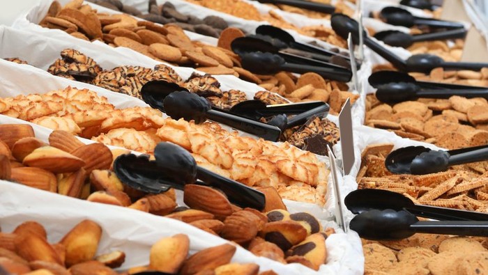 A close up of hands and food exchanging at a communty fair, fete or market stall. A typical bake or cake sale.