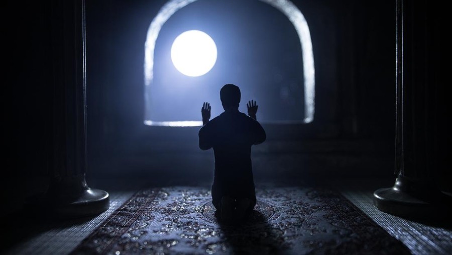 Doa Nabi Yunus A realistic Arabian interior miniature with window and columns. Silhouette of muslim praying on carpet near window. Festive greeting card, invitation for Muslim holy month Ramadan Kareem. Selective focus