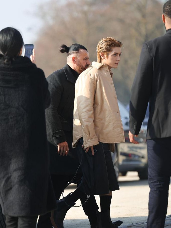 Idol K-Pop tersebut tampil maskulin dalam balutan outfit berwarna hitam yang dipadukan dengan outer berwarna khaki./ Foto: Getty Images/Jacopo Raule
