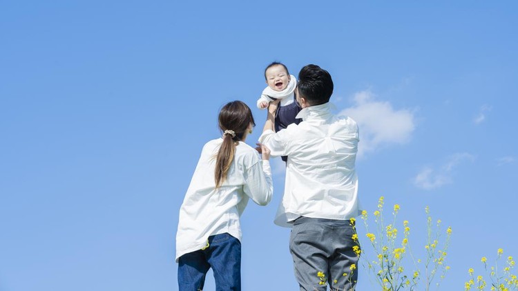 1309939432 Parents holding their baby high under the blue sky