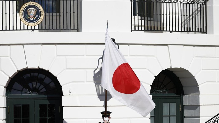 Seorang anggota pasukan kehormatan memegang bendera nasional Jepang. (Bloomberg via Getty Images)