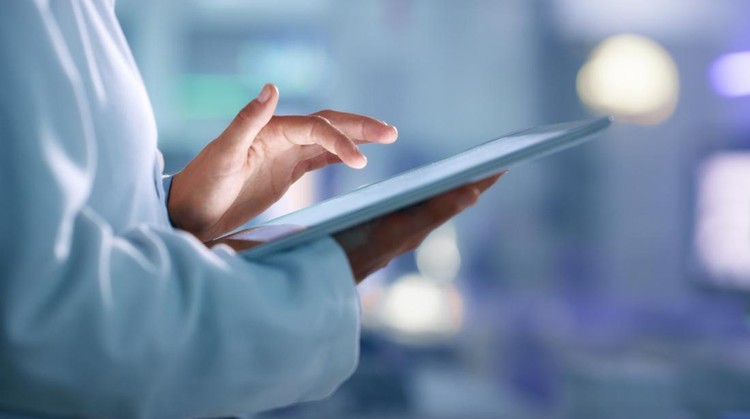 Doctor, researcher or scientist browsing the internet on a tablet for information while working at a lab, science facility or hospital. Expert, medical professional or surgeon searching the internet