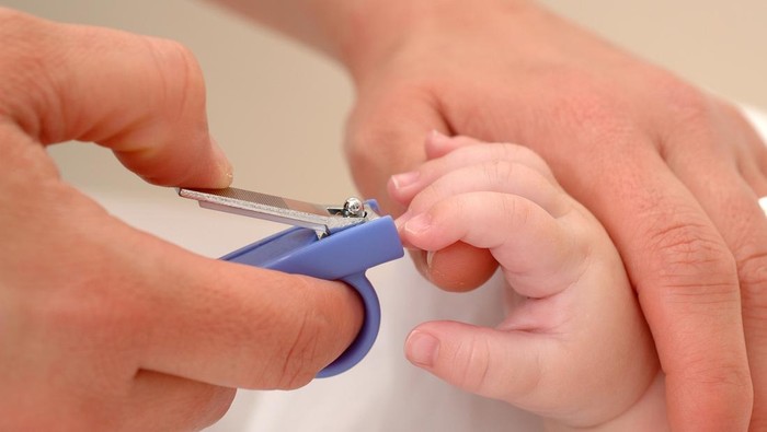 Close up of mum cutting babies long nails