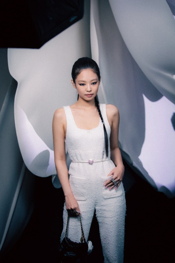Hadir di fashion show Chanel, Jennie tampil sporty dan chic mengenakan jumpsuit putih aksen belt dan tas Chanel 22 versi mini. Foto: Courtesy of Chanel