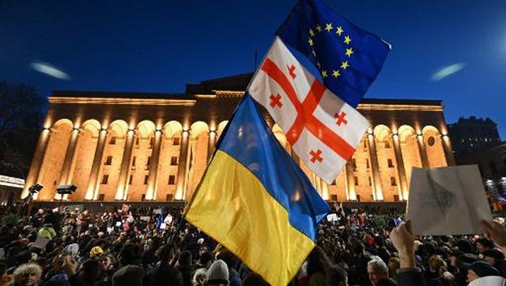 A protesters wave the Georgian, Ukrainian and European flags during a demonstration called by Georgian opposition and civil society groups outside Georgia's Parliament in Tbilisi on March 8, 2023. - At least two thousand demonstrators marched through the capital of Georgia, Tbilisi, on March 8, 2023 to protest government plans to introduce a 