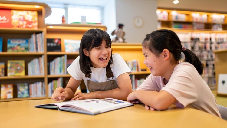 Ilustrasi Anak Cerdas Friends relaxing together in the library. Okayama, Japan.
