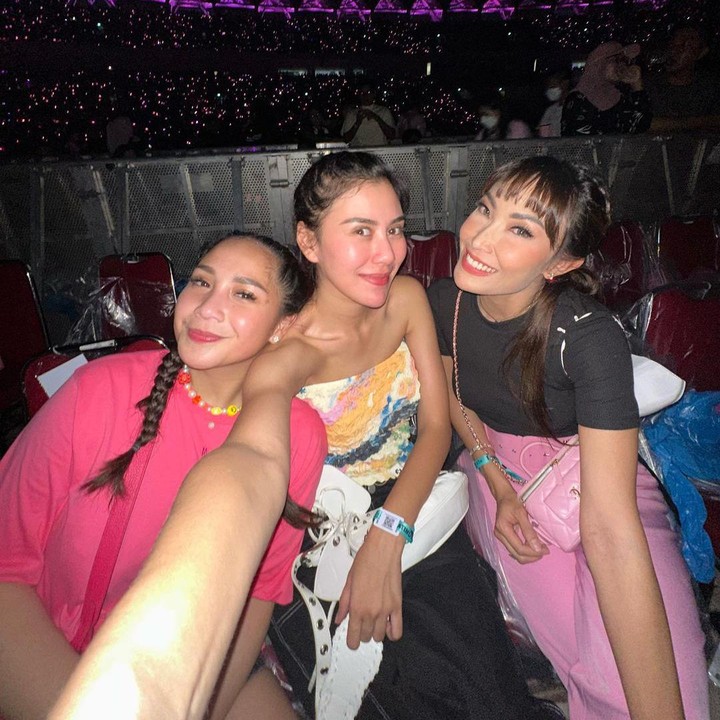 <p>Keceriaan mereka bertambah ketika sang sahabat, Ayu Dewi, turut hadir bergabung menyaksikan konser. Ia tampil memakai busana dengan nuansa warna pink dan hitam agar <em>matching</em> dengan BLACKPINK. (Foto: Instagram @syahnazs)</p>
