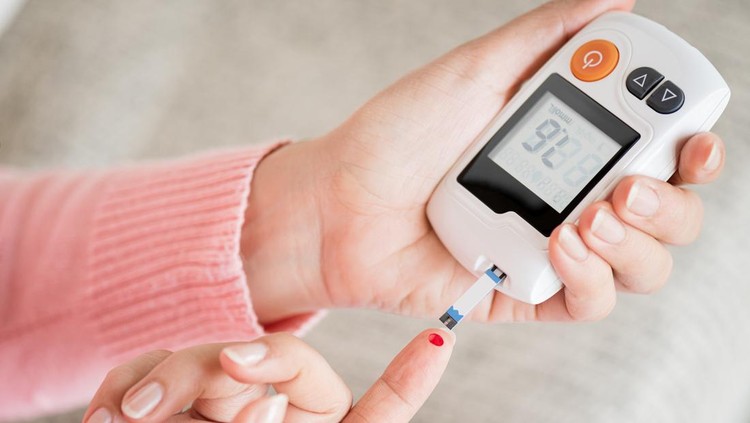 Close up woman hands checking blood sugar level by glucose meter for diabetes tester using as medicine, glycemia, healthcare and medical concept.