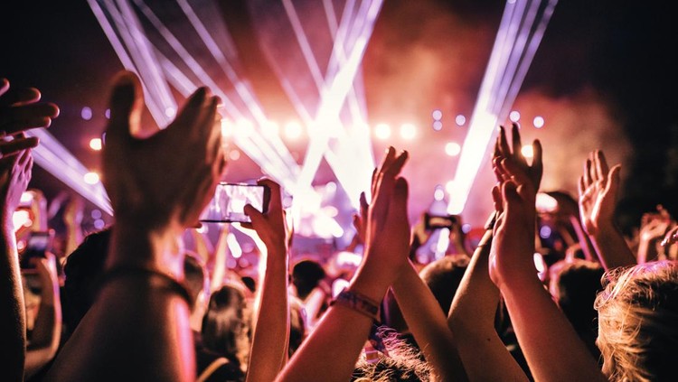 Rear view of large group of people enjoying a concert performance.  People in foreground are released.