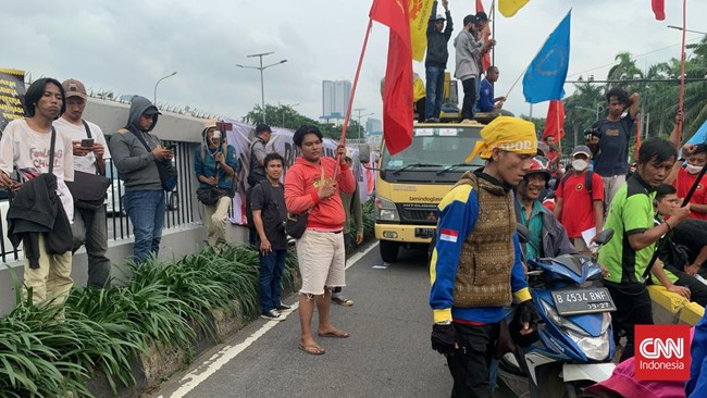Massa aksi unjuk rasa tolak Perrpu Cipta Kerja (Ciptaker) mengadang jalan di depan area Gedung DPR RI, Selasa (14/3).
