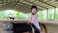 <p>Baby Guzel kerap diajak menunggangi kuda bersama kedua orang tuanya, nih. Tanpa rasa takut, Guzel naik ke atas kuda di arena stable. (Foto: Instagram @guzelimalisyakieb)</p>
