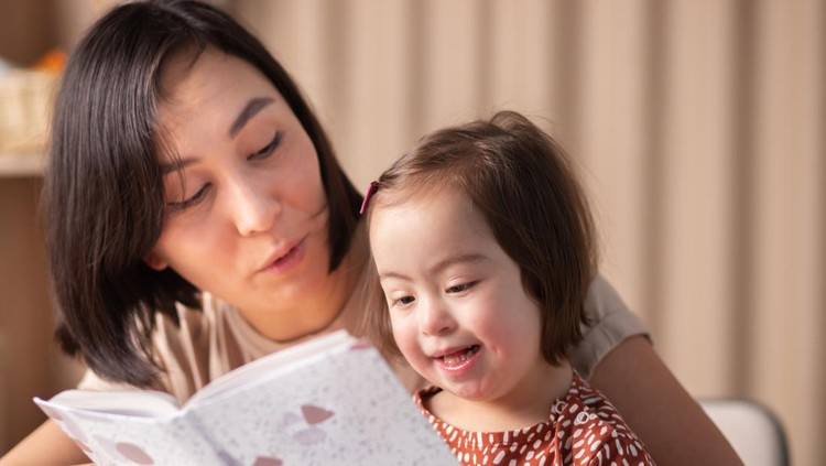 cute baby girl with down syndrome with book studying