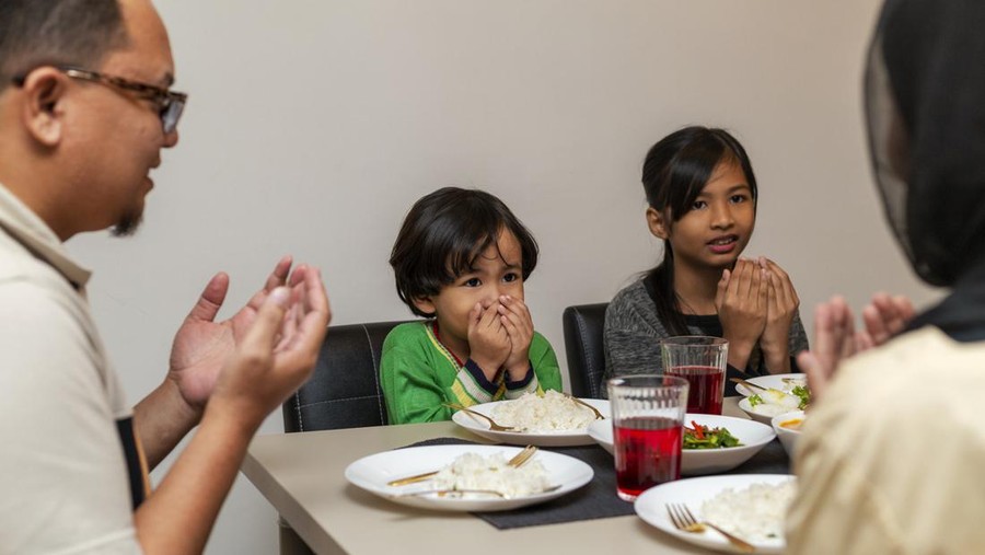 Asian Muslim saying Bismillah on table praying before opening of fast during the month of ramadan