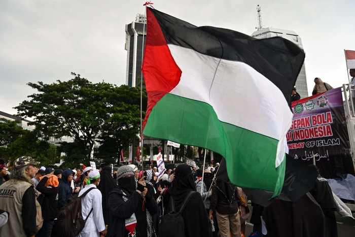 An Indonesian woman holds the flag of Palestine during a rally in Jakarta on March 20, 2023 to demand the Indonesian government to reject the participation of Israel's team in the upcoming 2023 FIFA U-20 World Cup, which is to be hosted by Indonesia between May 20 and June 11. (Photo by ADEK BERRY / AFP) (Photo by ADEK BERRY/AFP via Getty Images)
