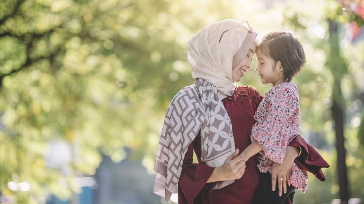 Ilustrasi Memberi Anak Pemahaman Puasa an asian modern muslim malay woman with hijab and sunglasses carrying her daughter outdoor on the street of kuaala lumpur bonding time