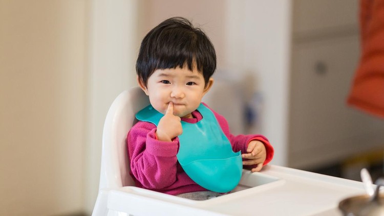 Cute baby Sitting in a high chair waiting for to eat dinner