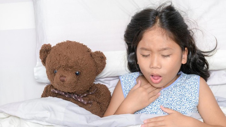 Little girl is coughing and sore throat lying on bed with toy bear, Health care concept
