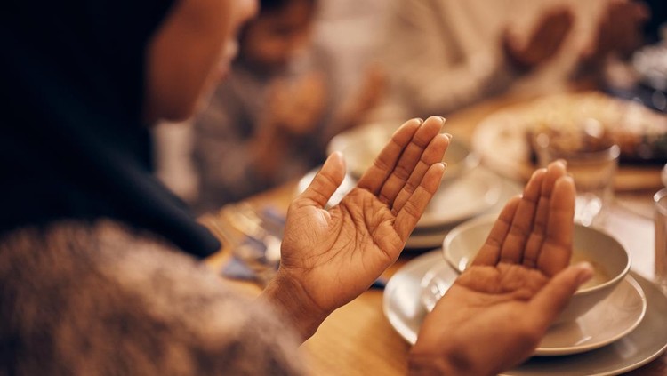 1376088159 Close-up of religious Muslim woman and her family praying before the meal at dining table on Ramadan.