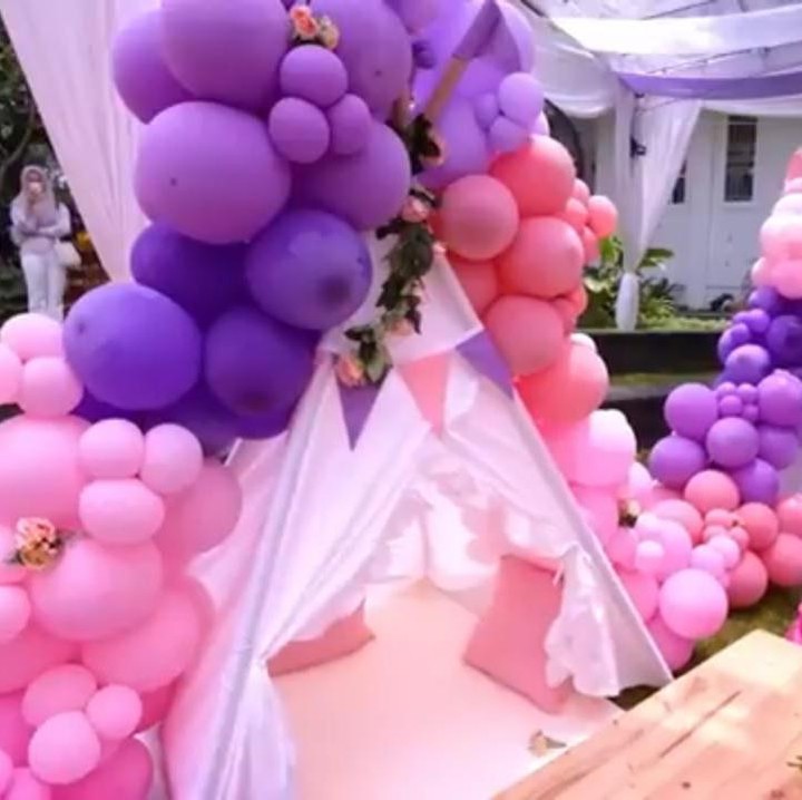 <p>Dekorasi pesta dibuat semirip mungkin dengan aslinya, nih. Terdapat pula balon-balon yang didominasi dengan warna pink dan ungu. (Foto: YouTube Tasyi Athasyia)</p>