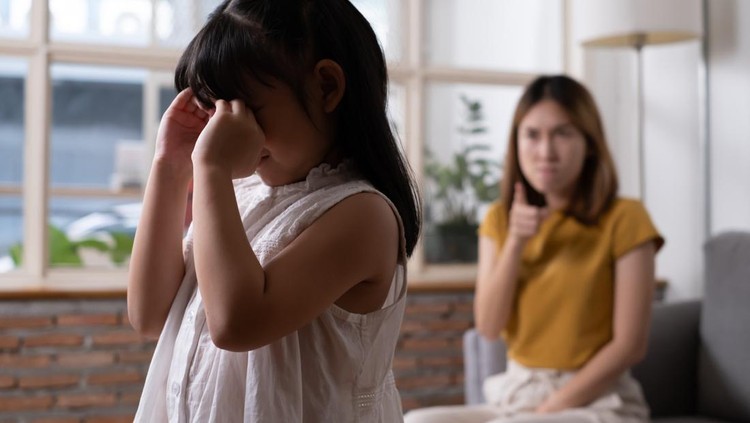 Indoor shot of young Asian girl crying and cover her ear with hands and feel sad while get scold and shout with angry from her angry mother. Child abuse that can cause a problem for children.