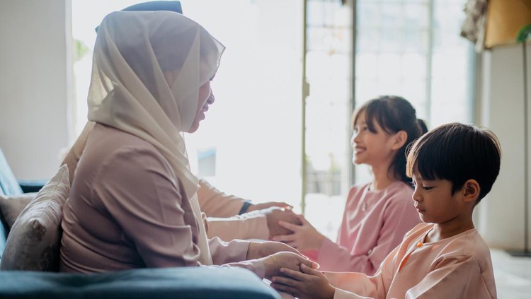 Malay Muslim children in traditional clothings asking forgiveness to their parents during Hari Raya Aidilfitri celebration
