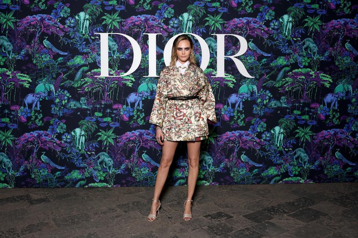 Gaya edgy diusung Cara Delevingne dalam balutan mantel pendek berhiaskan bordir bersama kemeja dan belt. Foto:Getty Images/Courtesy of Dior
