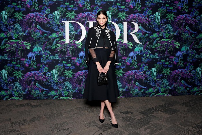 Layering bisa jadi cara untuk membuat tampilan serba hitam terlihat lebih stand out seperti ditunjukkan Karlie Kloss yang memadukan crop jacket aksen bordir dengan blus dan rok. Foto: Getty Images/Courtesy of Dior