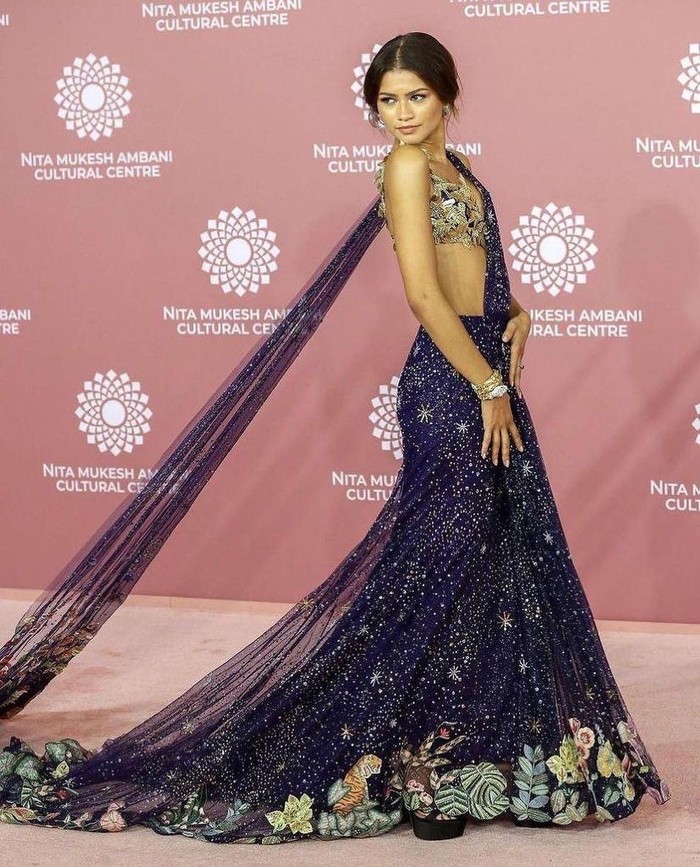 Zendaya tampil di karpet merah jambu NMACC dalam balutan busana etnik kreasi Rahul Mishra. “Verdure” saree gown dibuat dengan bordiran tangan, terdiri dari manik-manik dan warna-warni bunga dan bralette “Flying Cranes”. Foto: instagram.com/rahulmishra_7