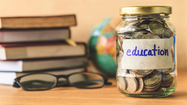 Coins in glass jar with education label, books,glasses and globe on wooden table. Financial concept.