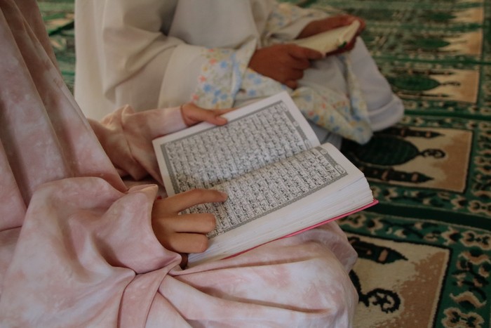 Ilustrasi perempuan membaca Al-Qur'an/Foto: Unsplash/Ed Us