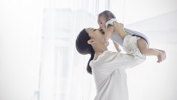 Mother embracing her baby girl while sleeping, lifestyle concept. Portrait of young woman and cute little baby in home interior. Motherhood concept