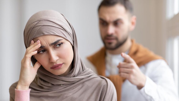 1300327515 Husband Shouting At Depressed Wife Tired Of Domestic Violence And Victimization Standing At Home. Selective Focus. Relationship With Abuser And Family Conflicts
