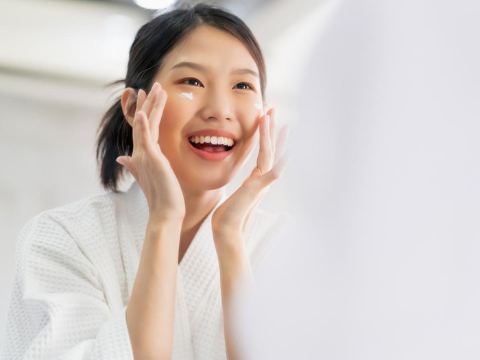 Foto ilustrasi seorang perempuan yang mengaplikasikan produk moisturizer.