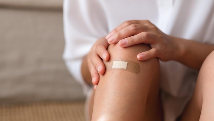 Closeup image of a young woman with adhesive bandage, medical plaster, band aid on her knee