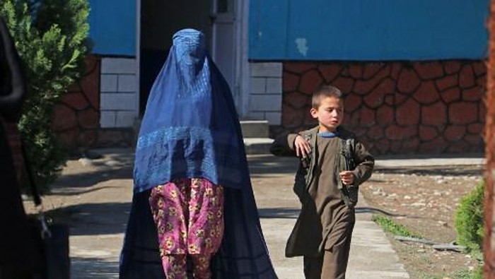 An Afghan woman walks along with a boy through a pathway in Fayzabad district of Badakhshan province on March 21, 2023. (Photo by OMER ABRAR / AFP)