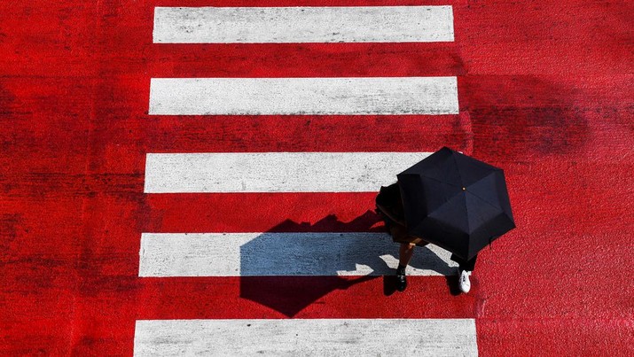 Orang-orang memegang payung saat menyeberang jalan saat suhu mencapai rekor 45,4 derajat Celcius (113,7 Fahrenheit) di Bangkok, Thailand, 22 April 2023. (REUTERS/Chalinee Thirasupa)