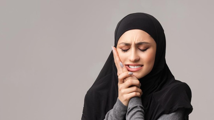 Aching tooth. Unhappy arabic woman in hijab suffering from teeth pain, having caries, touching her cheek with miserable face expression, panorama