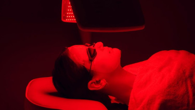 Young woman having red LED light facial therapy treatment in beauty salon. Beauty and wellness concept