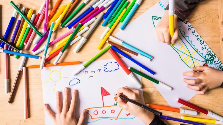646884464 The hands of two small children who are making drawings with colored markers on a desk