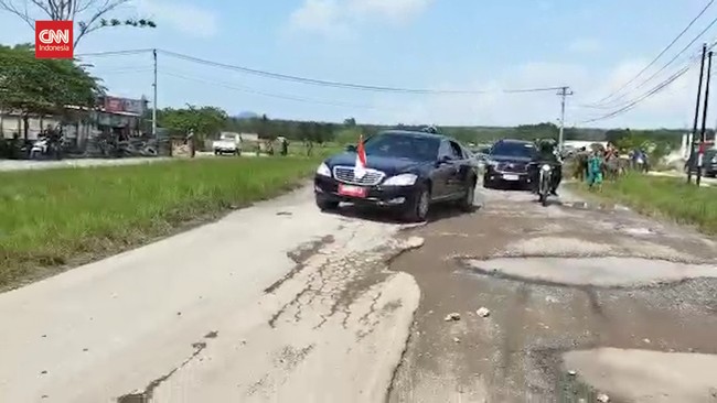 Jokowi dengan mobil Mercedes-Benz S 600 Guard melintasi jalanan rusak di Lampung. Mobil menyusuri jalan dengan lubang-lubang menganga.